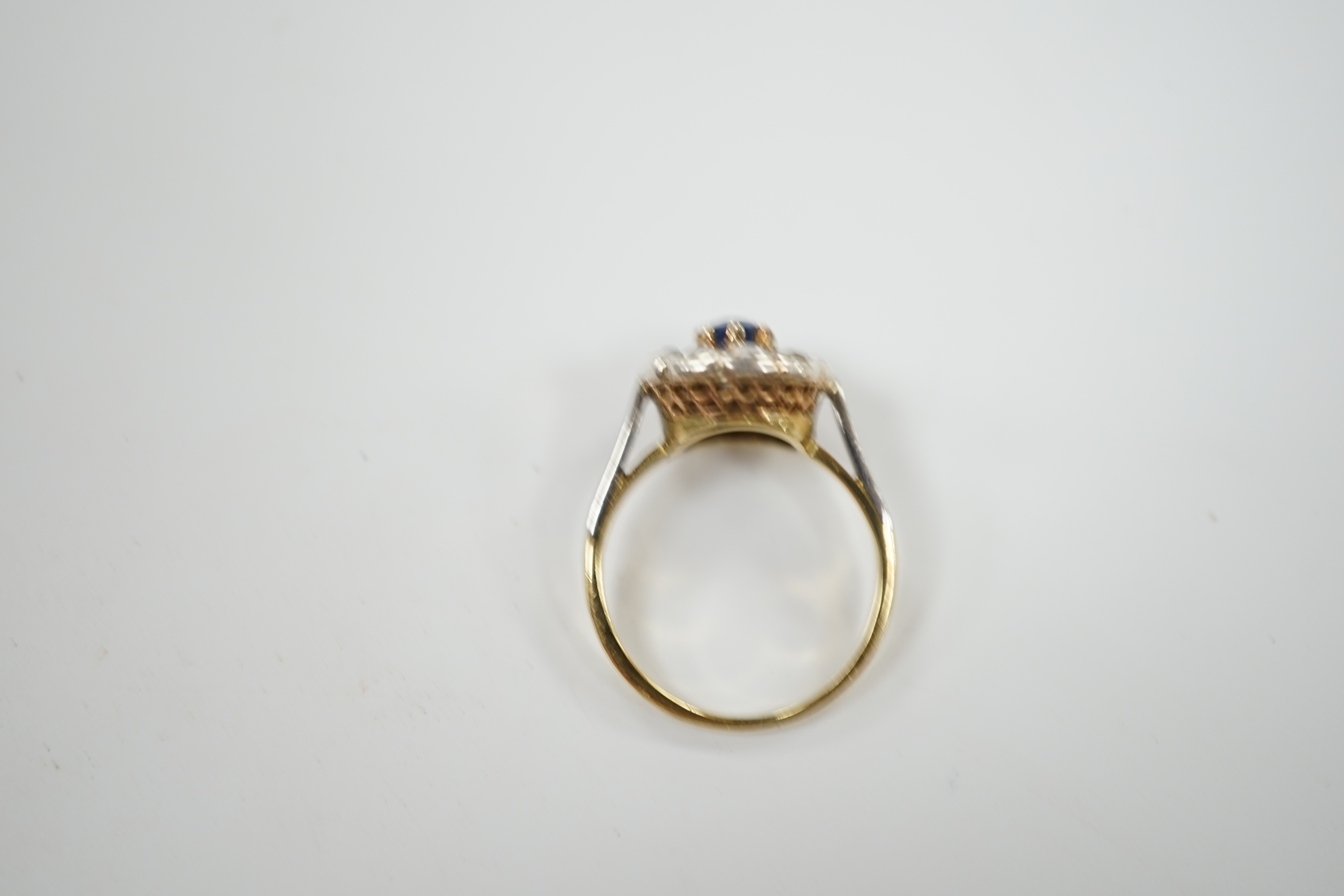 An early 20th century 18ct, single stone sapphire and ten stone rose cut diamond set circular cluster ring, size L, gross weight 3.9 grams.